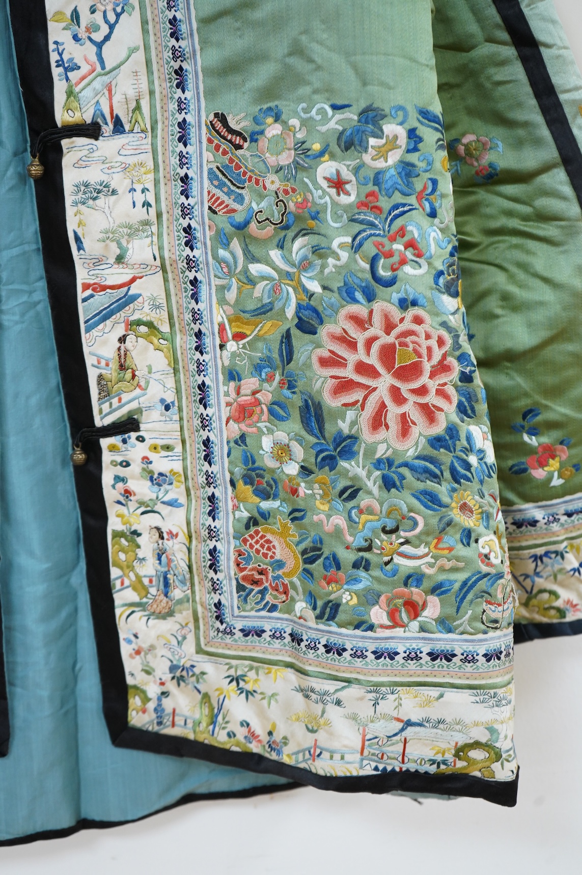 An early 20th century Chinese green silk polychrome embroidered jacket. Worked with Chinese knot embroidery and stem stitch into flowers, butterflies and bats, edged with woven silk ribbon and a figurative embroidered bo